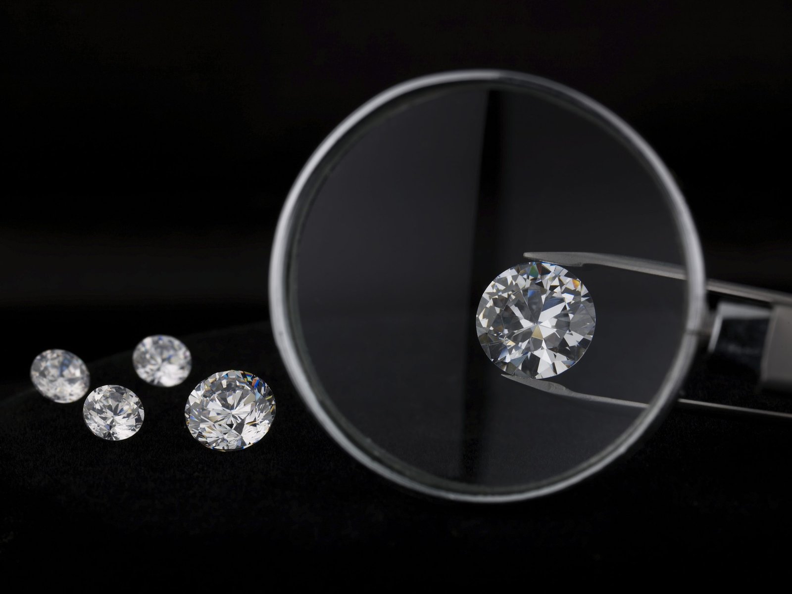 Loose lab-grown diamond held with tweezers under a jeweller's loupe