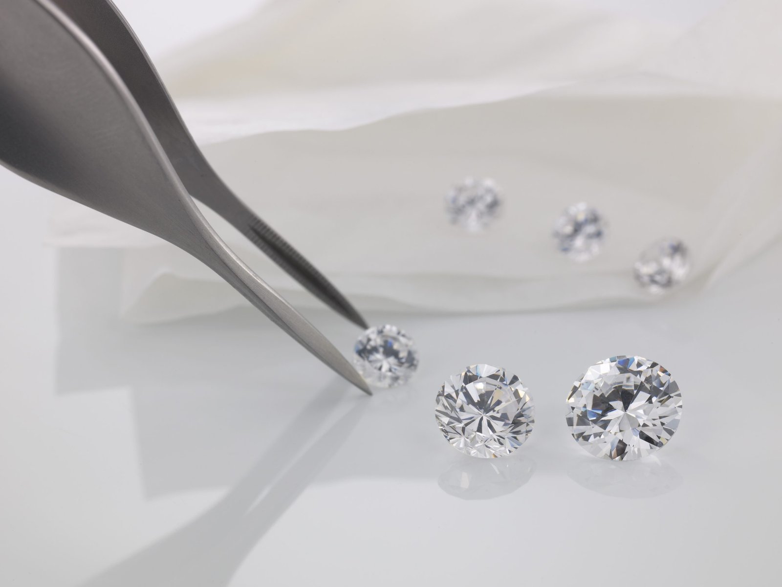 Gemologist selecting lab-grown diamonds with tweezers on a light background